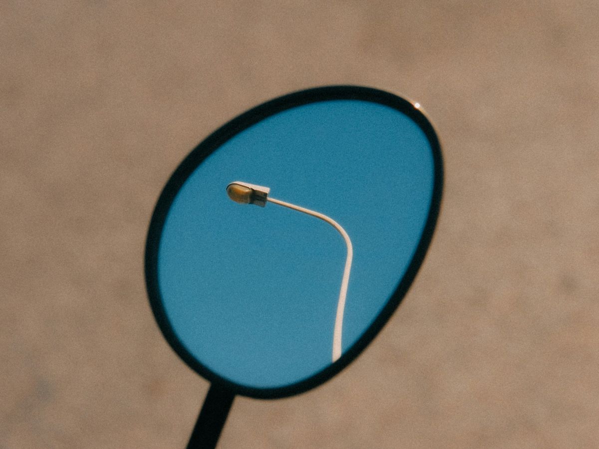 a close up of a mirror with a street light in the reflection