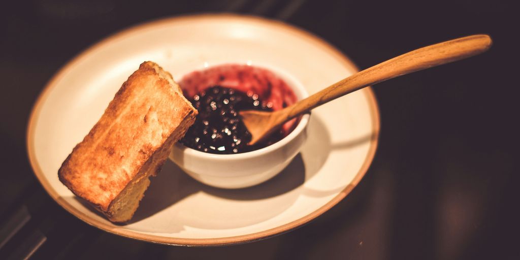 blueberry jam in bowl with spoon and slice of bread