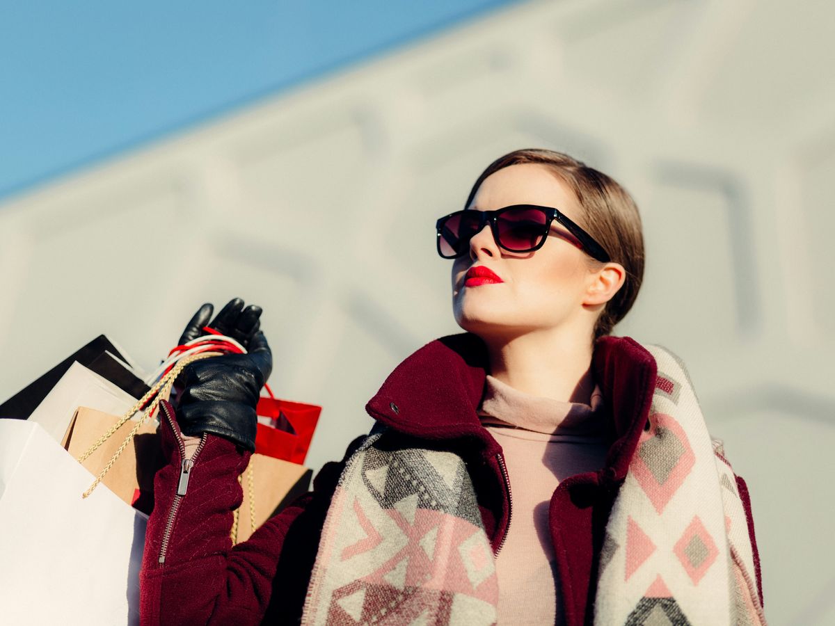 shallow focus photography of woman holding shopping bags during day