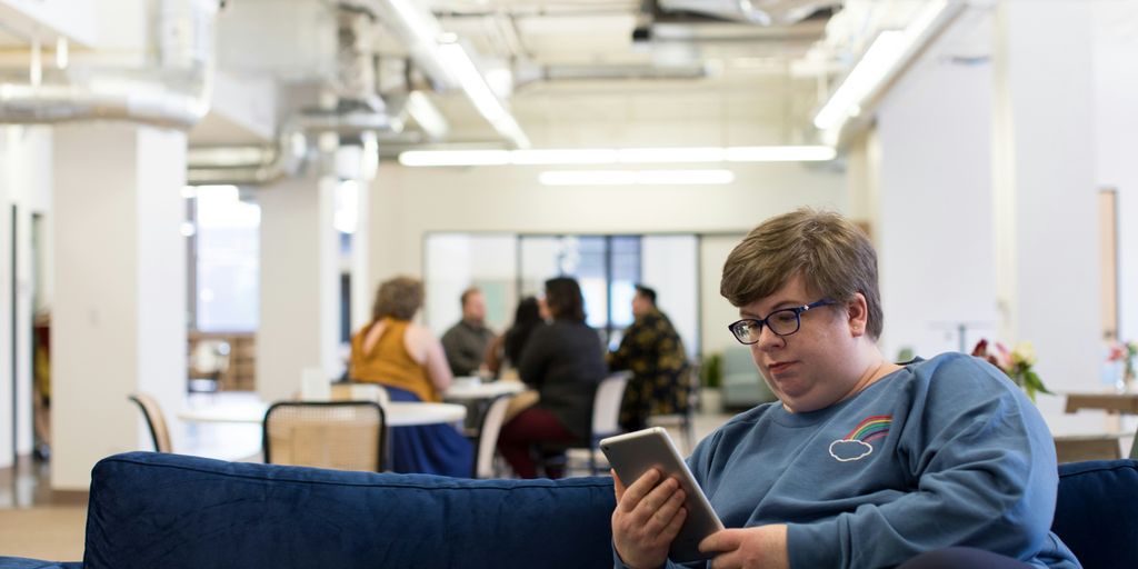 woman holding tablet computer sitting on blue couch