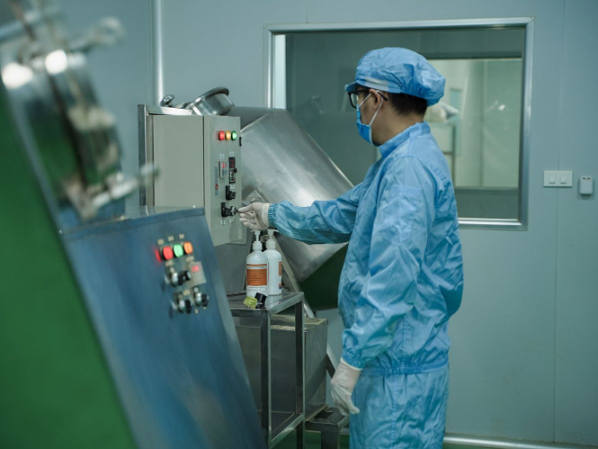 A person in protective gear operates machinery in a lab.