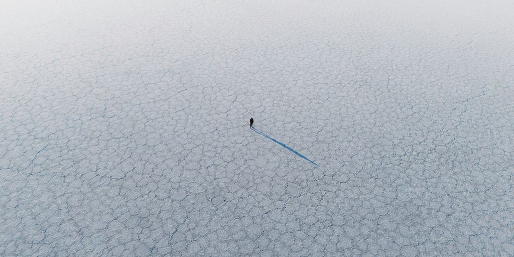 A person walks alone on a textured surface.