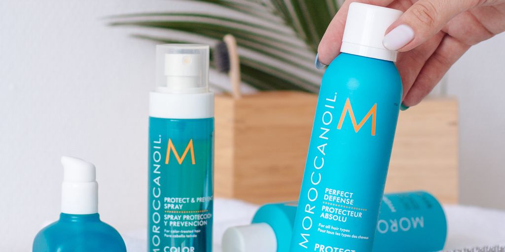 Haircare products displayed with a hand holding a spray bottle.