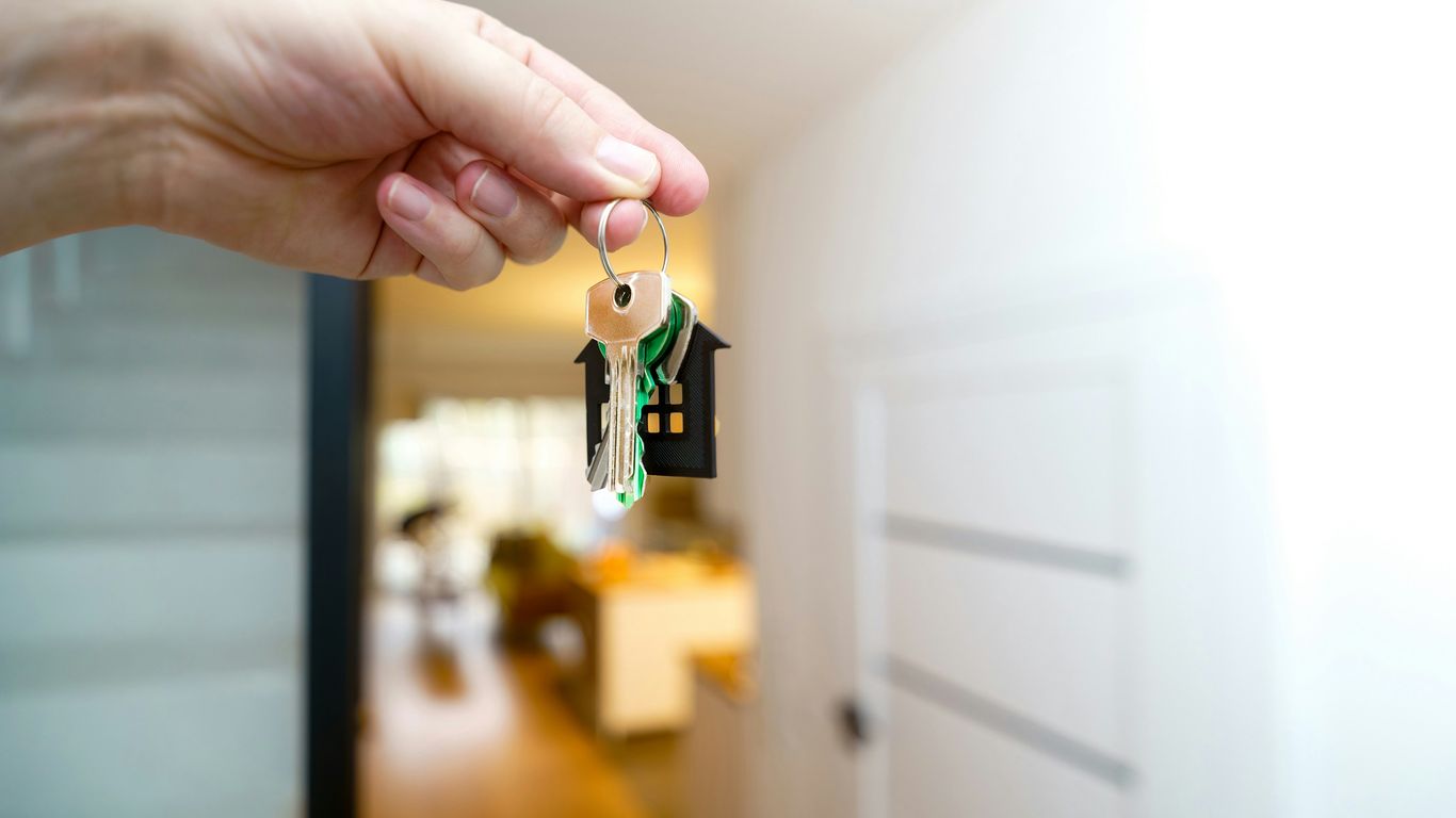 Holding house keys in front of the entrance.