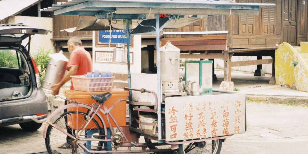 a man standing next to a bike with a cart attached to it