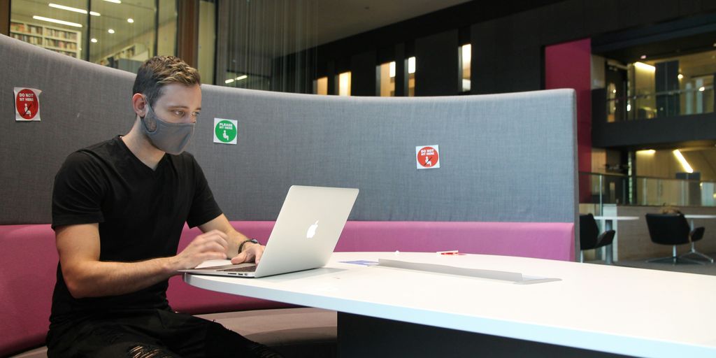 man in black polo shirt using macbook