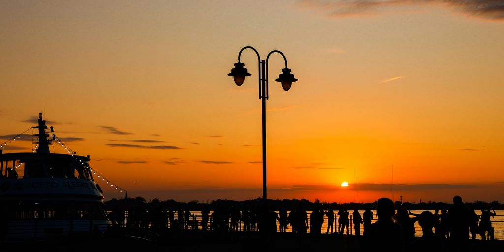 a group of people standing next to a boat at sunset