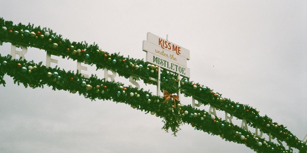 a street sign decorated with christmas garland and lights