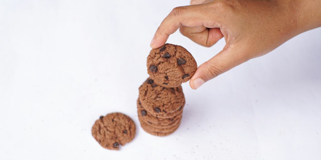 Hand is stacking chocolate chip cookies.
