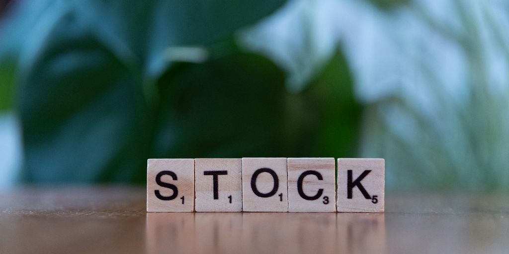 A wooden block spelling the word stock on a table