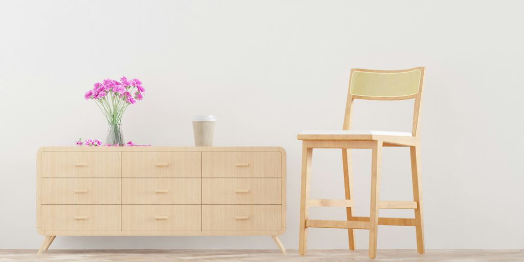 a chair and a dresser with a vase of flowers on it