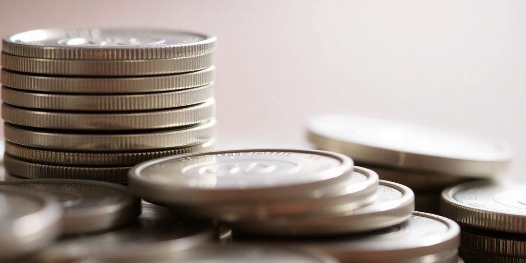 Pièces d'argent brillantes empilées sur fond doux.