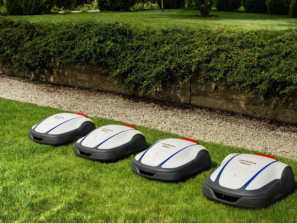 Four robotic lawn mowers on a neatly kept lawn.
