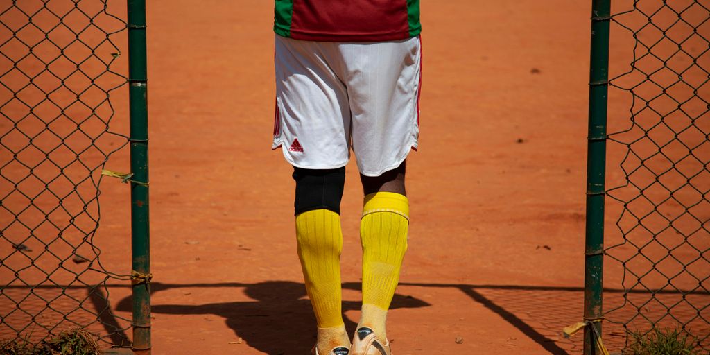 person in red shirt and yellow shorts standing on brown field