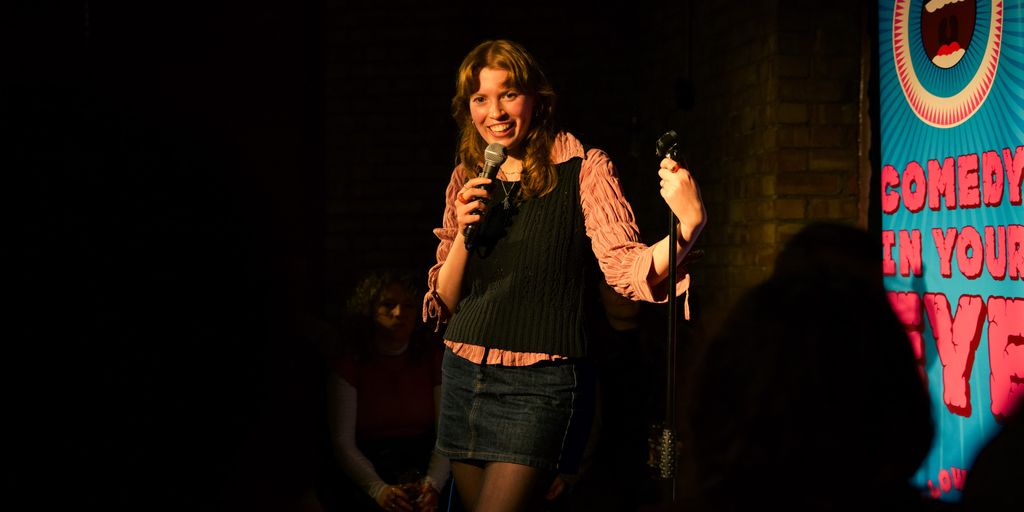 A person performs comedy on stage with a microphone.