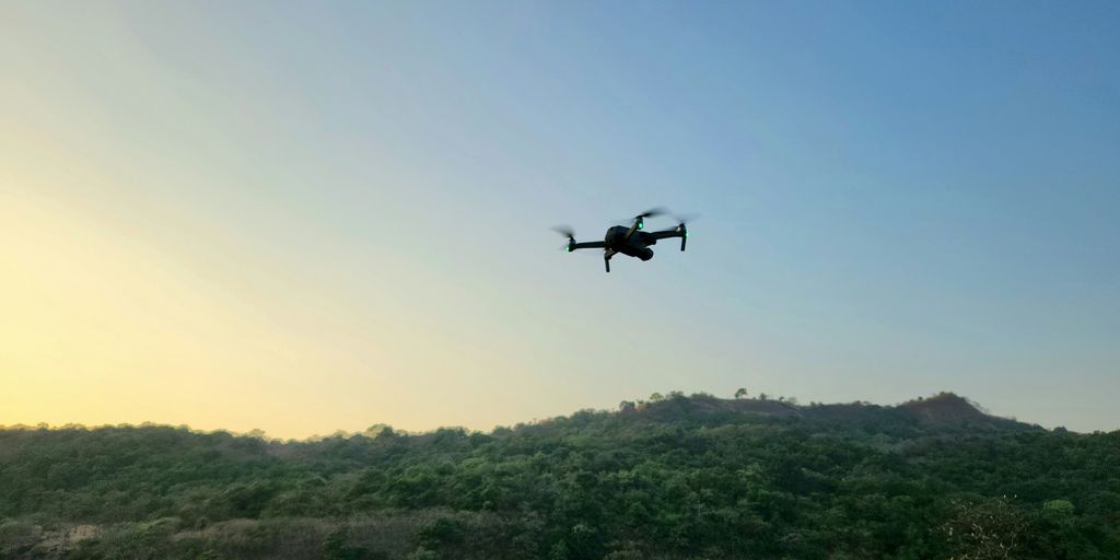 a small plane flying over a lush green hillside