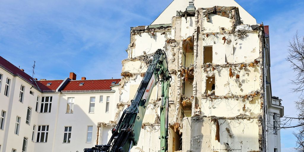 a building being demolished with a crane in front of it