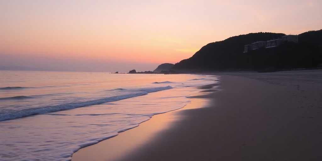 Calm beach at sunrise with soft waves and pastel skies.
