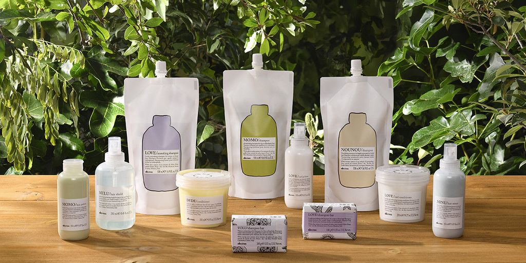 Assorted skincare products displayed on wooden surface with greenery backdrop.