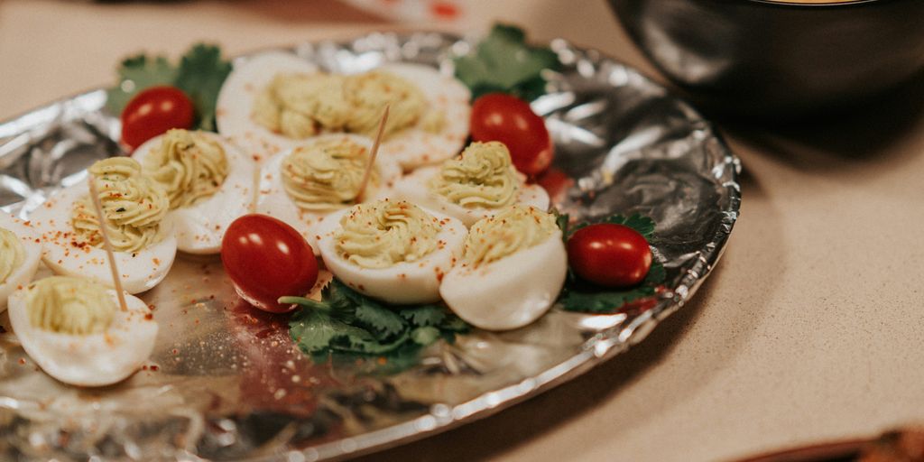 A silver plate topped with deviled eggs and cherry tomatoes