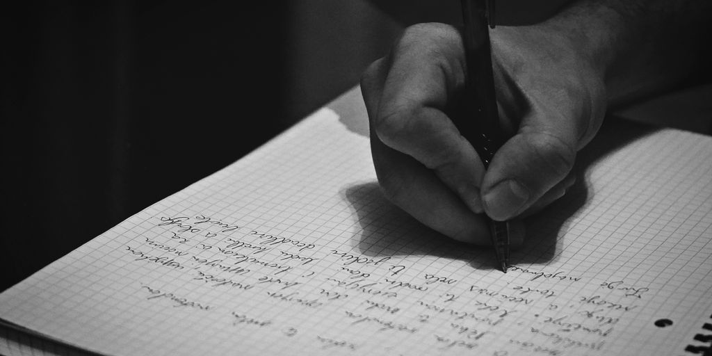 A person writing on a notebook with a pen