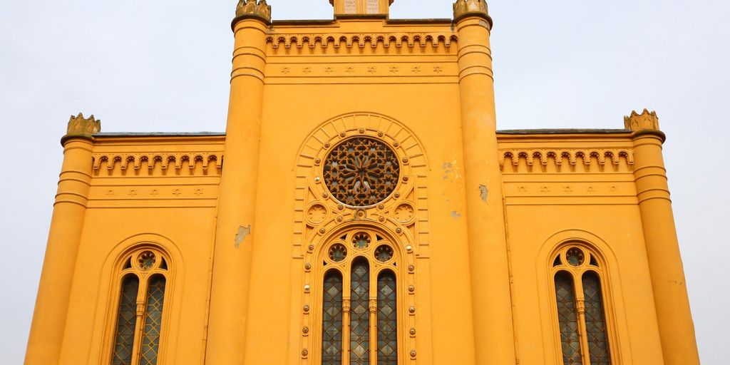 A large yellow building with a clock on it's side