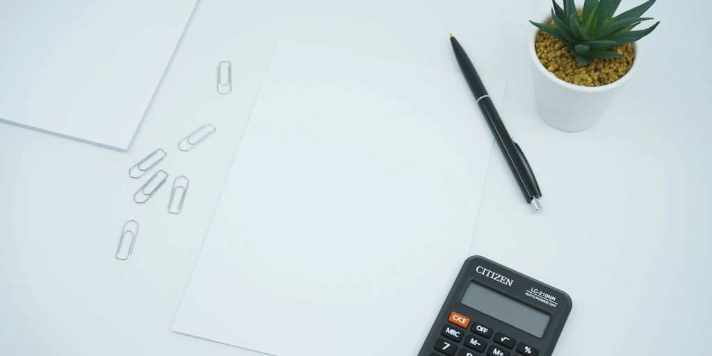 black calculator beside black pen on white printer paper