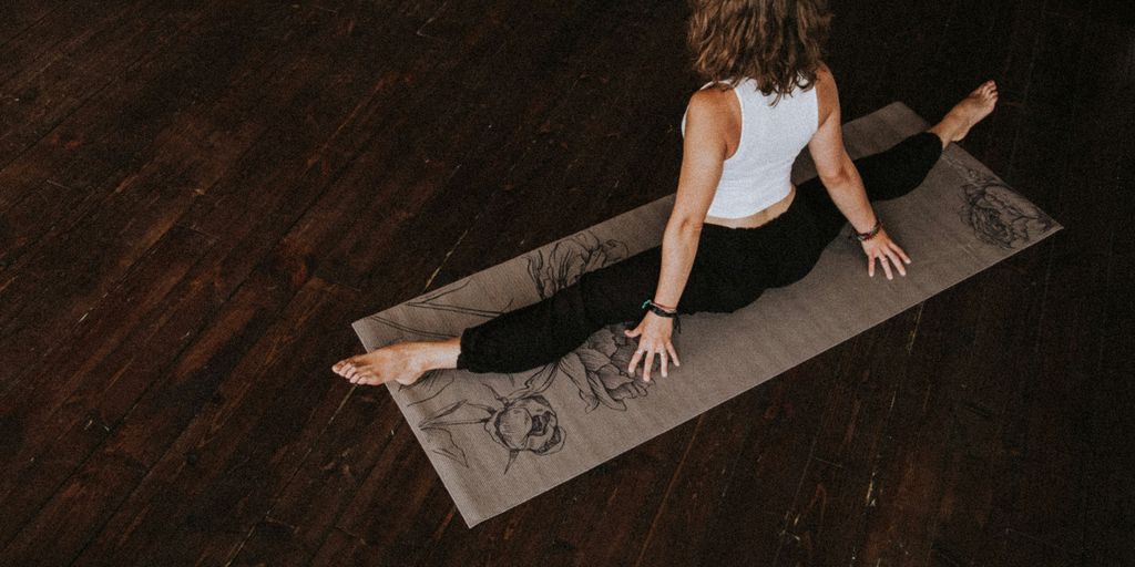 woman in white crop-top and black leggings doing yoga