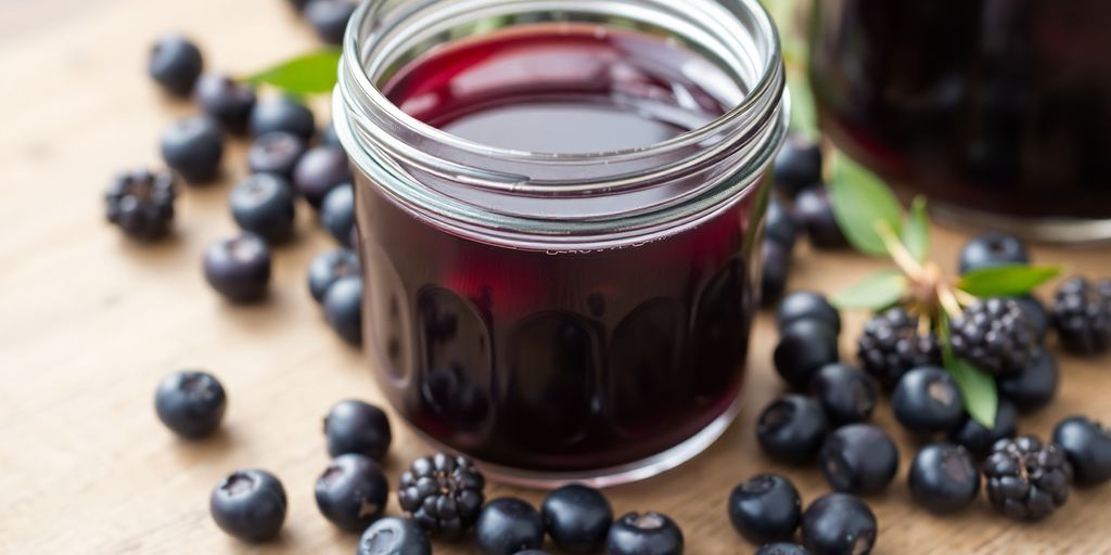 Elderberry syrup in a glass jar with fresh elderberries.