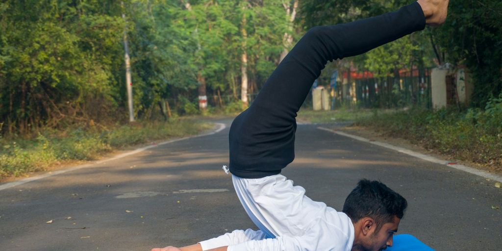 A man doing a yoga pose on a blue mat