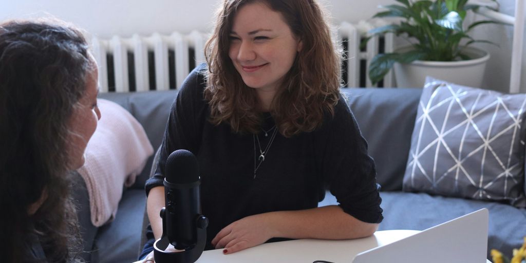 woman in black half-sleeved shirt sitting while facing woman and smiling