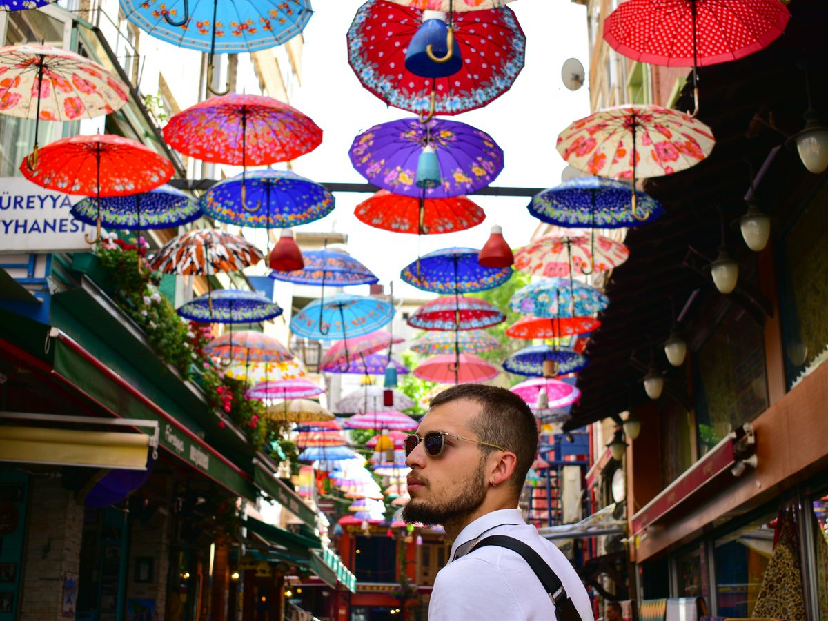 man wearing white dress shirt on street with umbrellas