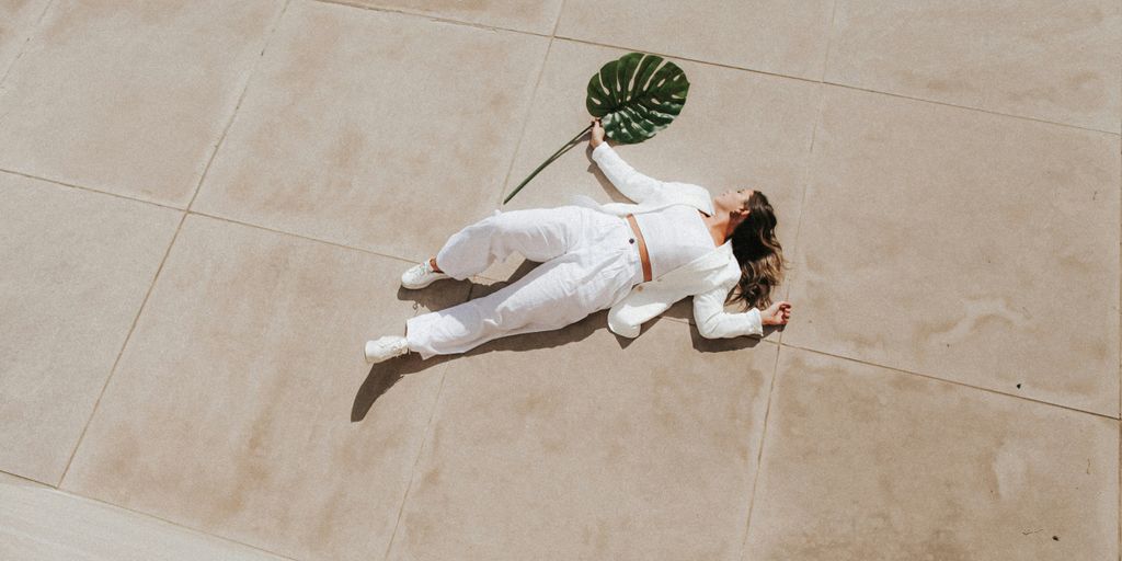 woman in white long sleeve shirt and white pants lying on green and white floor tiles