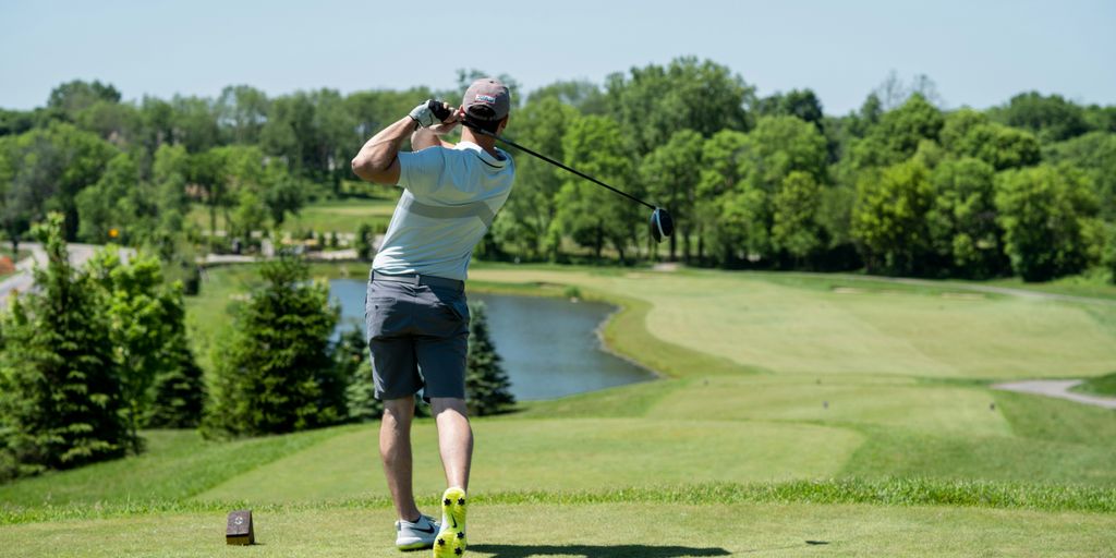 man in white t-shirt and black shorts playing golf during daytime