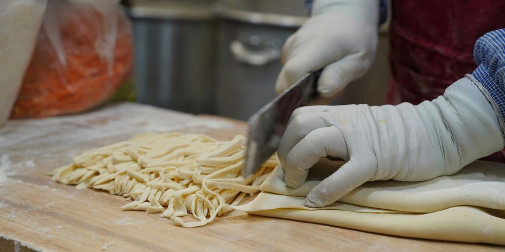 A person in a kitchen cutting up some food