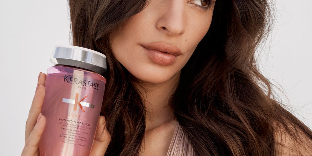 Person holding haircare product, looking calmly at the camera.