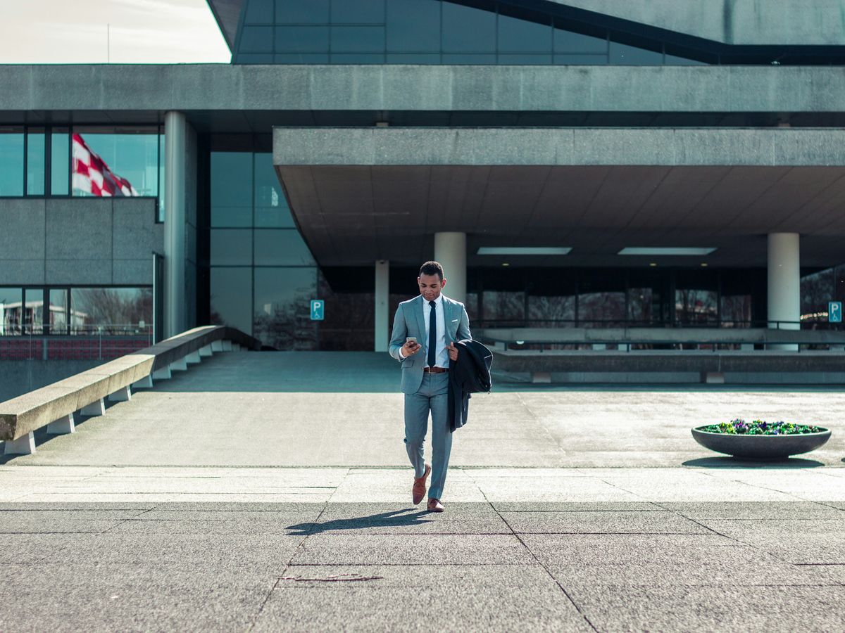 man walking while holding black coat