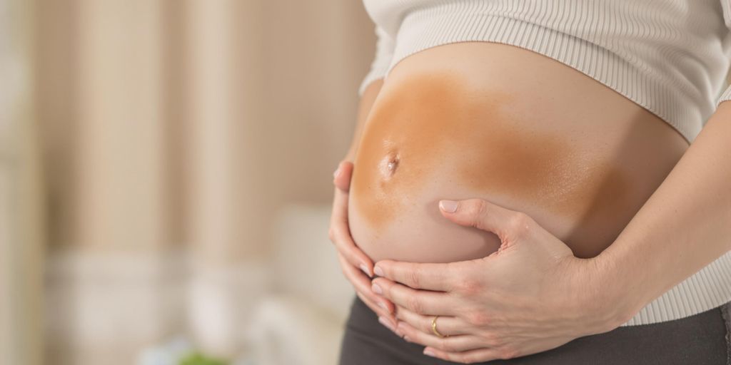 Woman with a concerned expression holding her abdomen.