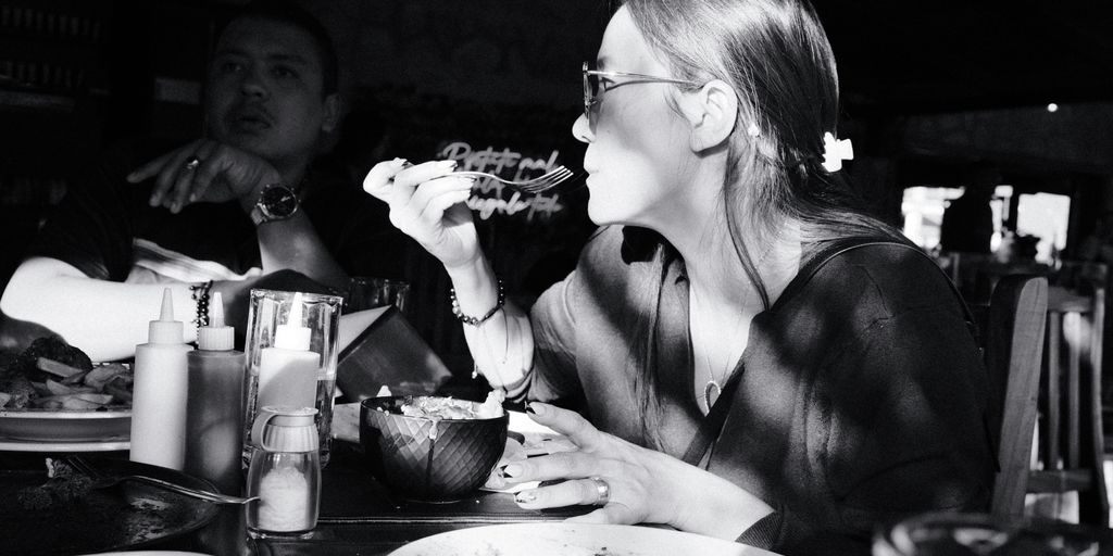 A woman sitting at a table eating a piece of pizza