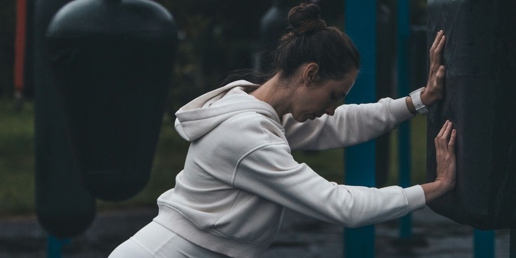 A woman stretches at an outdoor boxing gym.