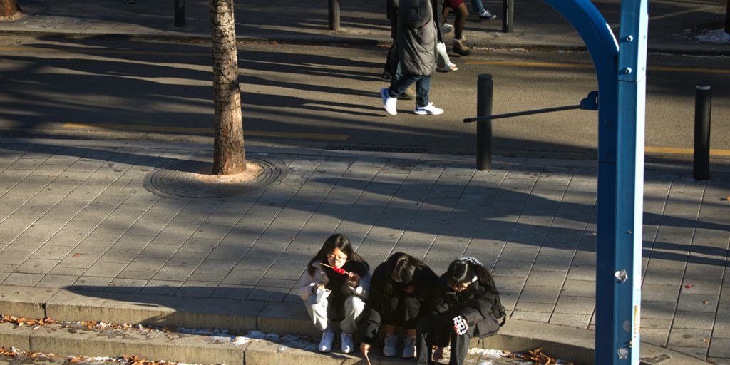 a group of people sitting on the side of a street