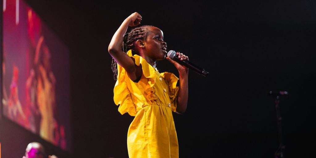 A girl in yellow sings on stage.