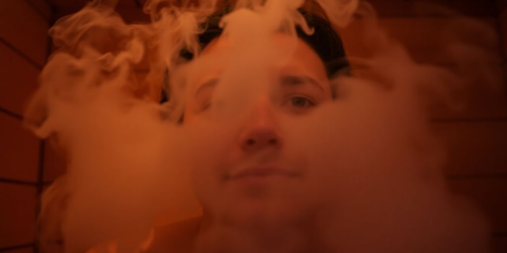 Steam rises from a person's face in a sauna.