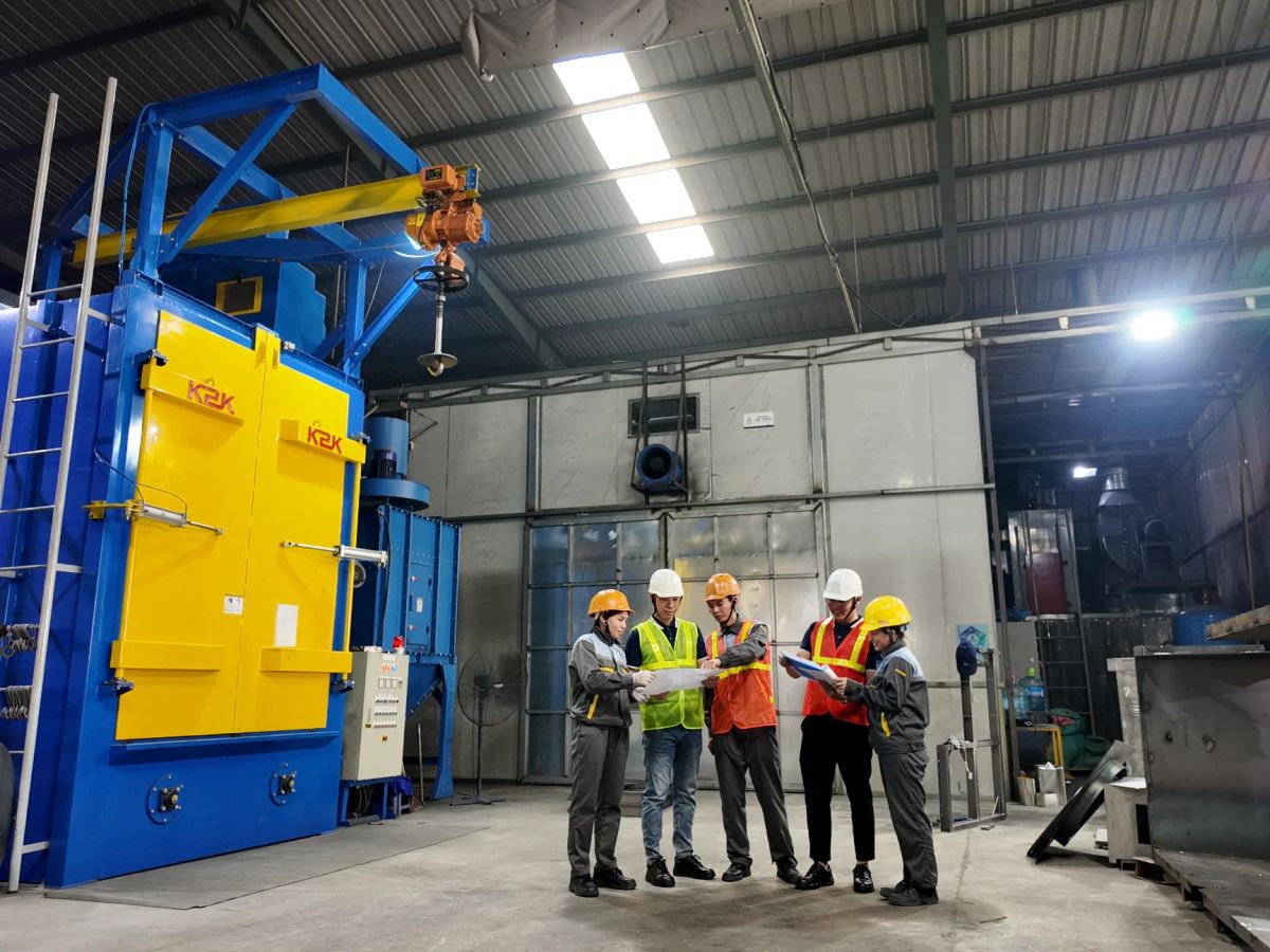 Workers discussing operations near industrial machinery in a factory.