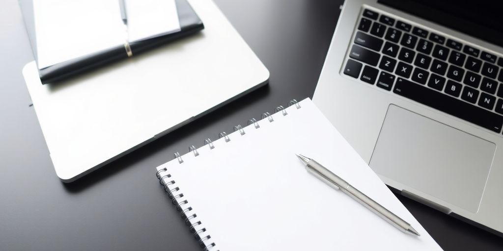 Laptop and notepad on a desk, ready for writing.