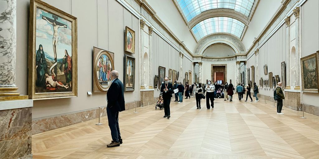 a group of people standing in a room with paintings on the walls