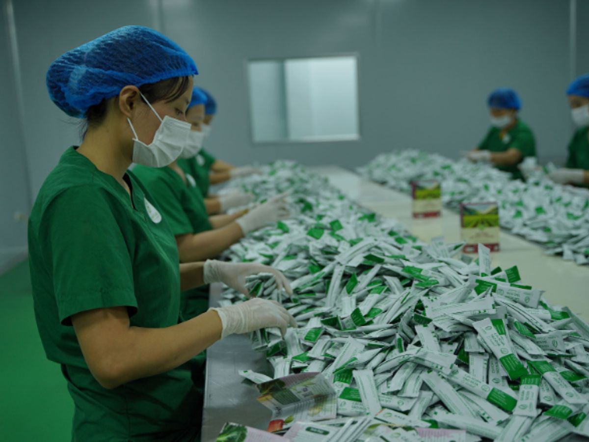 Workers in green uniforms sorting packages in a facility.