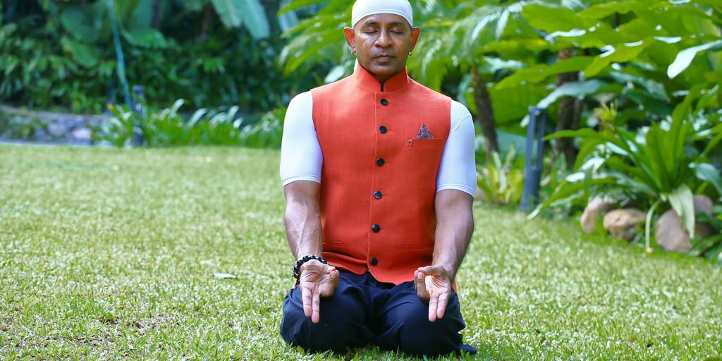 A man in a red vest sitting in the grass