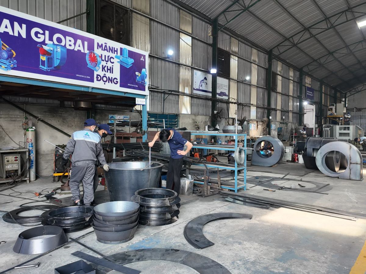 Manufacturing workshop with workers and machinery for production tasks.