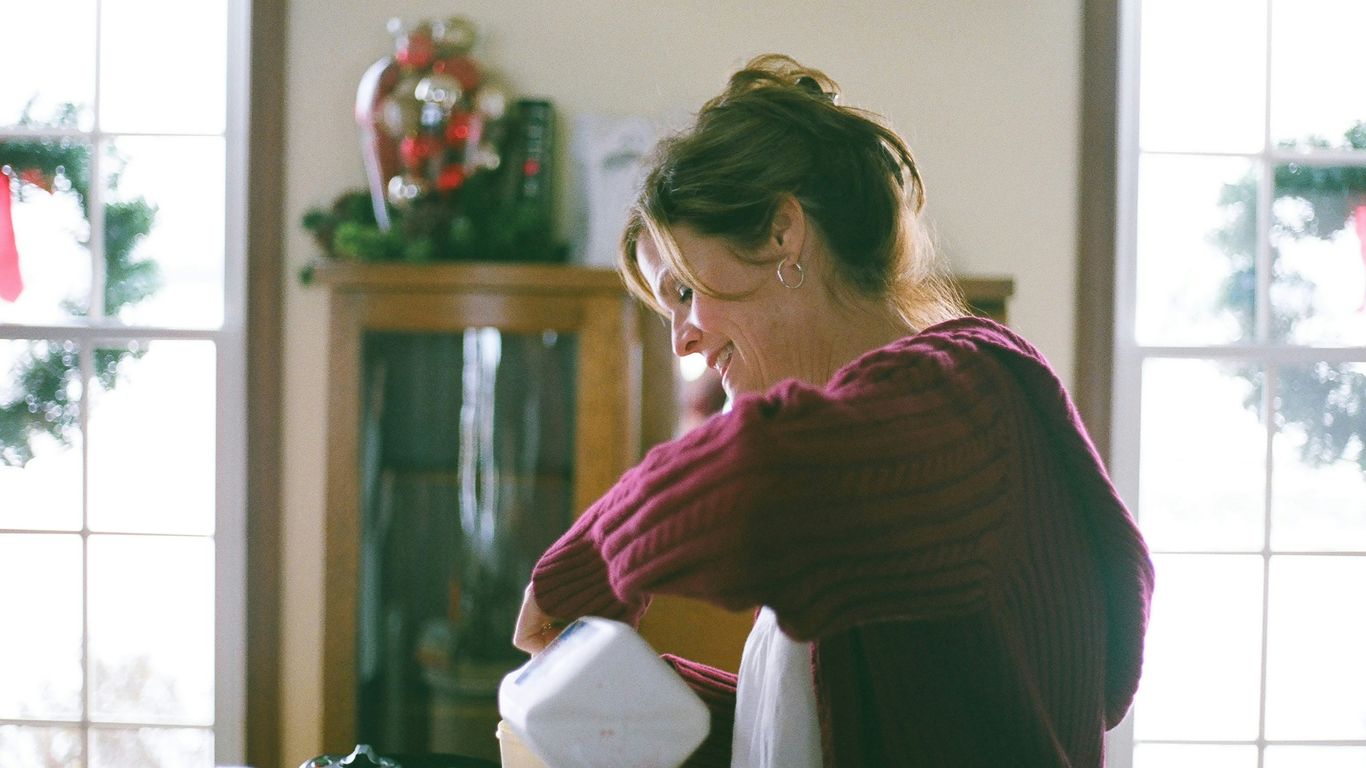 girl wearing maroon jacket holding white plastic bottle in room